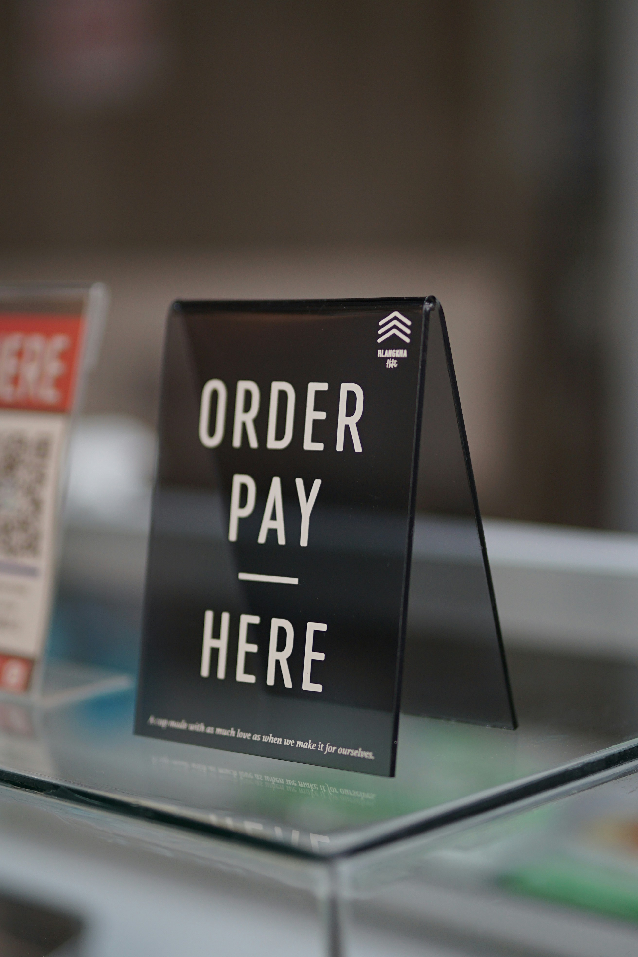 a sign that says order pay here on a glass table